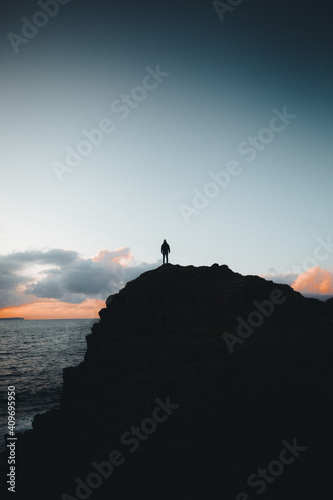 person on hill at sea sunset