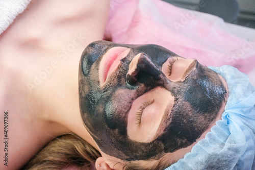 Young woman with carbon nanogel on her face in salon. photo