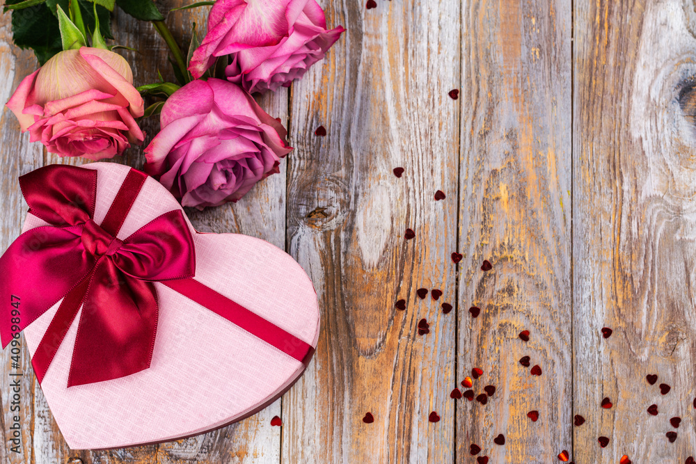 Pink roses and heart shaped gift box on wooden plank background. Greeting card for Valentine's day, March 8th or mother's day. White background. Copy space Pink roses and heart shaped gift box on wooden plank background. Greeting card for Valentine's day, March 8th or mother's day. White background. Copy space