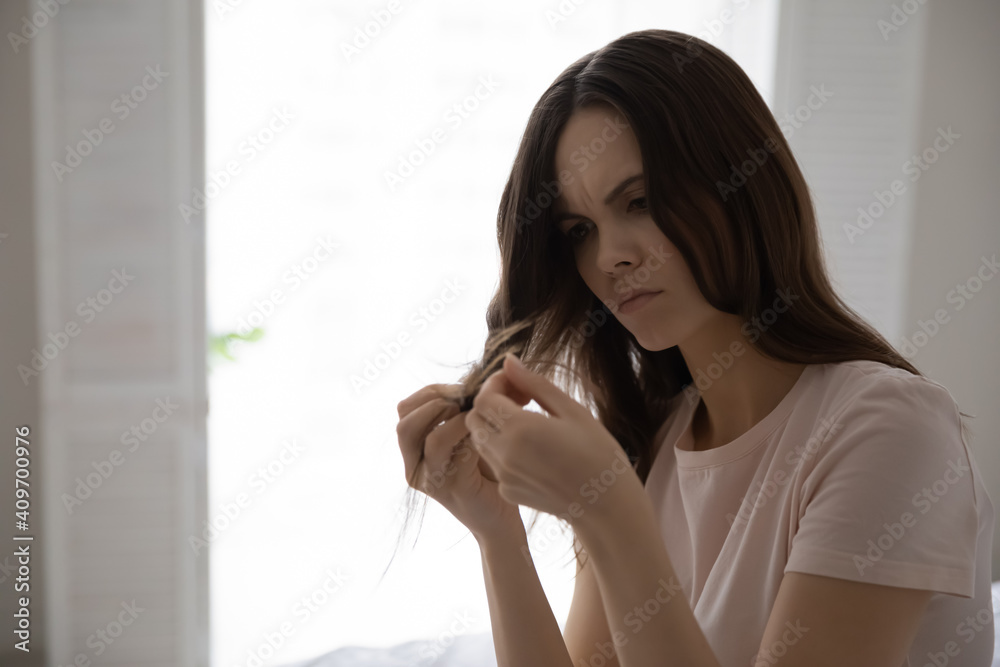 Upset young Caucasian woman look at hair distressed with thin damaged split ends. Unhappy millennial female frustrated by hairloss problem, need treatment or conditioner. Beauty concept. Upset young Caucasian woman look at hair distressed with thin damaged split ends. Unhappy millennial female frustrated by hairloss problem, need treatment or conditioner. Beauty concept.