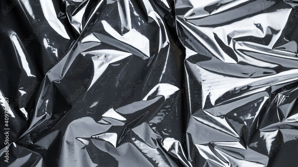 Smooth plastic texture. Black shiny film bag pattern. Wrap transparent dark cellophane background for packaging, product protection. Smooth plastic texture. Black shiny film bag pattern. Wrap transparent dark cellophane background for packaging, product protection.