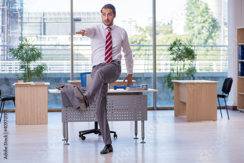 Young male employee doing sport exercises in the office