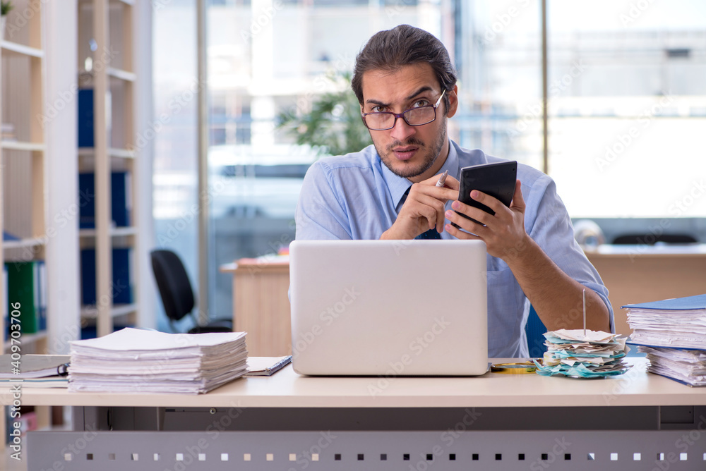 Young male accountant in budget planning concept Young male accountant in budget planning concept