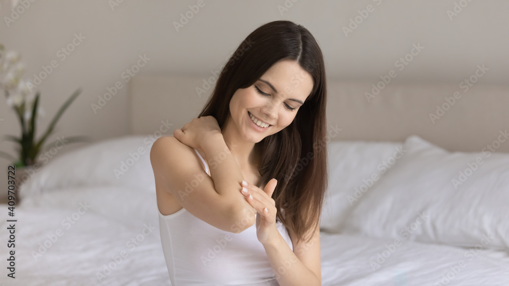 Smiling millennial Caucasian woman in home bedroom do daily beauty body procedures or treatment. Happy young female apply nourishing moisturizing body cream or balm for soft skin. Skincare concept. Smiling millennial Caucasian woman in home bedroom do daily beauty body procedures or treatment. Happy young female apply nourishing moisturizing body cream or balm for soft skin. Skincare concept.