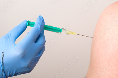 A doctor or nurse in rubber gloves gives a shot or injection. Vaccination against coronavirus, SARS-Cov-2.