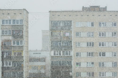 snowfall on the background of poor suburban apartment houses in the city photo