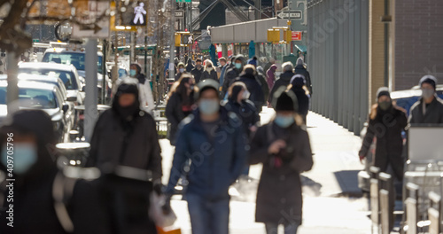 Crowd of people walking street wearing masks