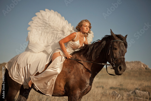 A girl on a horse with white angel wings at a horse