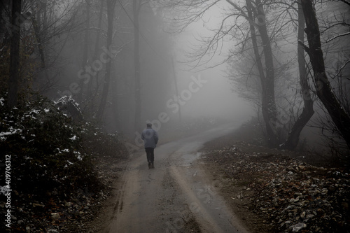man walking on a path in a strange dark forest with fog © zef art