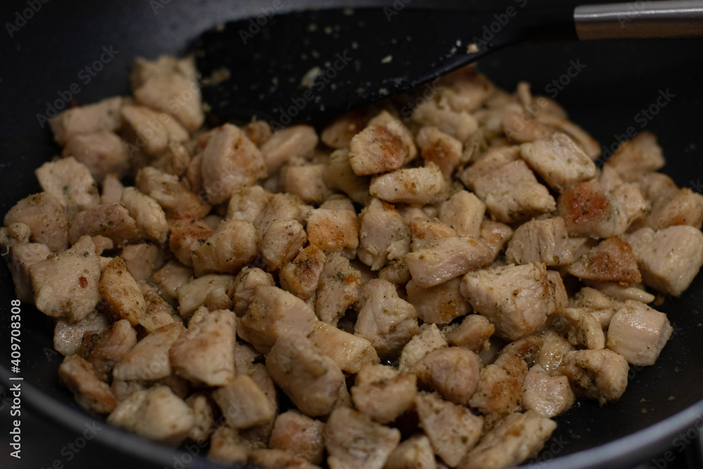 Cooking chicken cubes in a black frying pan Cooking chicken cubes in a black frying pan