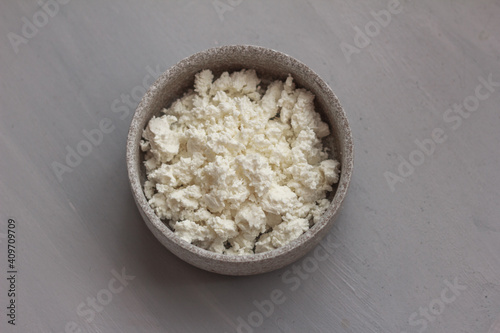 Fresh cottage cheese in a ceramic bowl on grey background. Top view, flat lay, copy space