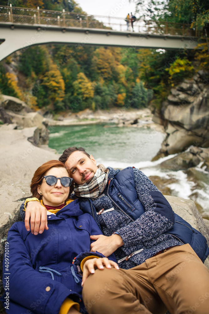 young beautiful couple travelers take a photo on the background of the river and forest