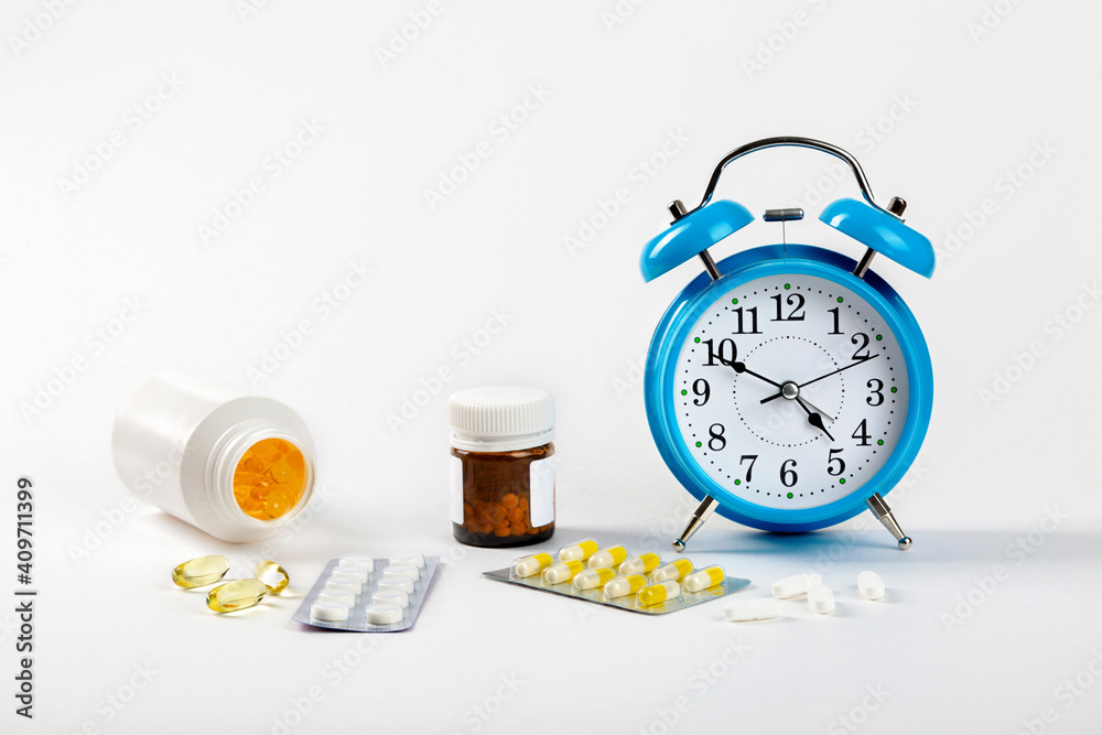 Time to take your pills. An alarm clock on a white background shows the