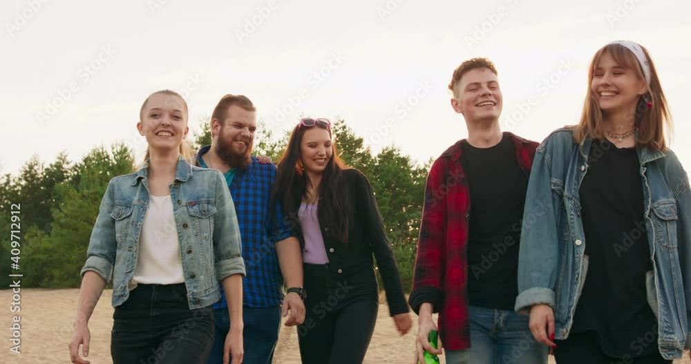 Tourism, travel, people, leisure and teenage concept - group of happy friends hugging and walking lakeside from back