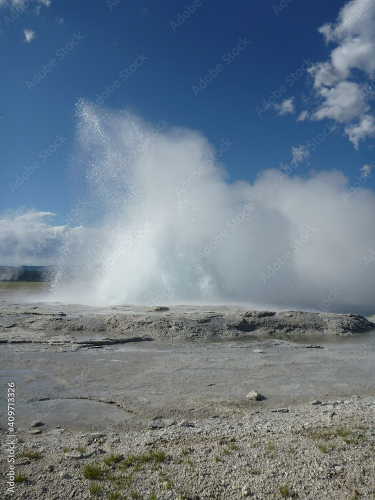 A small geyser at Yellowstone National Park erupting on a sunny day