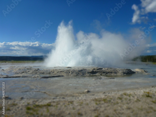 A small geyser at Yellowstone National Park erupting on a sunny day 