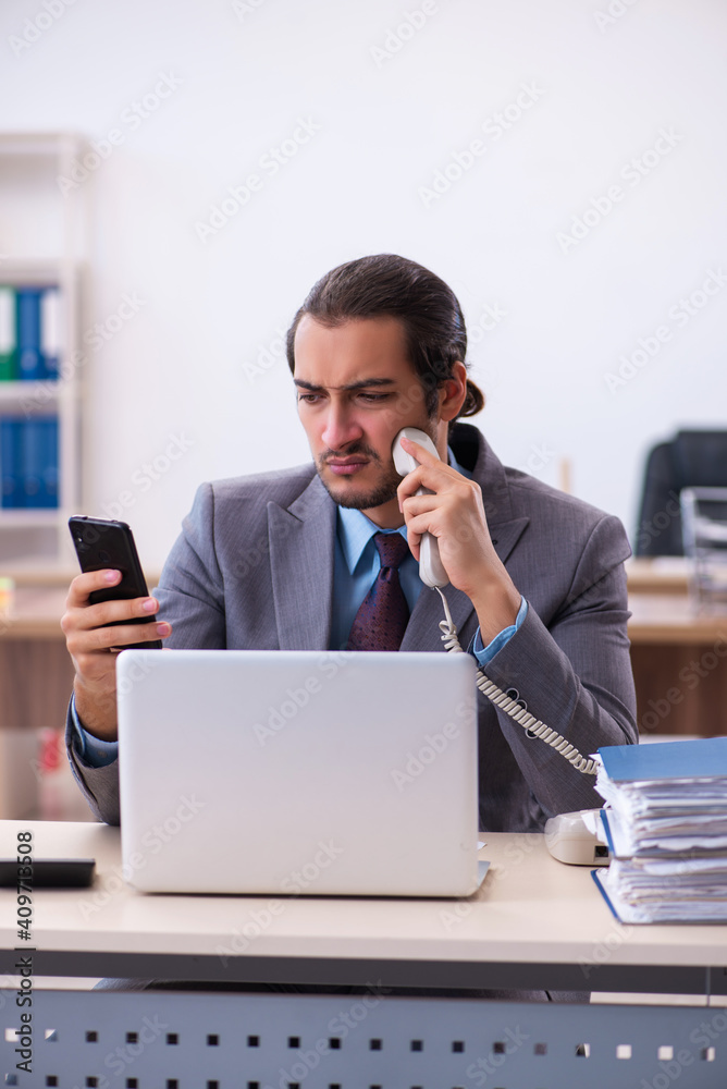 Young male employee unhappy with excessive work in the office Young male employee unhappy with excessive work in the office