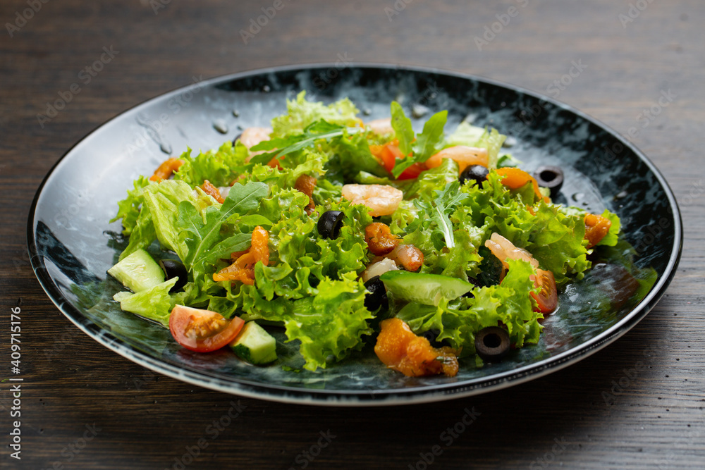 salad of shrimp, fresh cucumber and cherry tomatoes, Chinese cabbage and olives. salad dressed with olive oil. fish salad on a blue marble plate salad of shrimp, fresh cucumber and cherry tomatoes, Chinese cabbage and olives. salad dressed with olive oil. fish salad on a blue marble plate