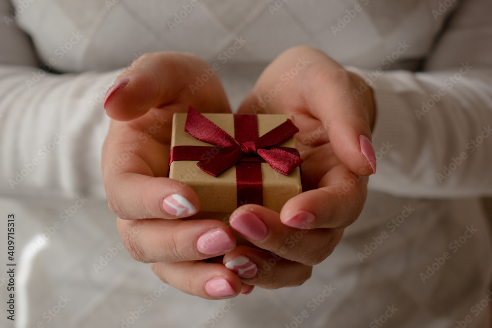 Woman hands holding a small present box with red ribbon over. Valentine gift box. Woman hands holding a small present box with red ribbon over. Valentine gift box.