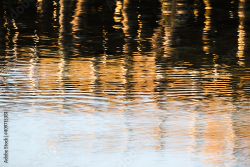 A wooden pier reflects on the water at sunset