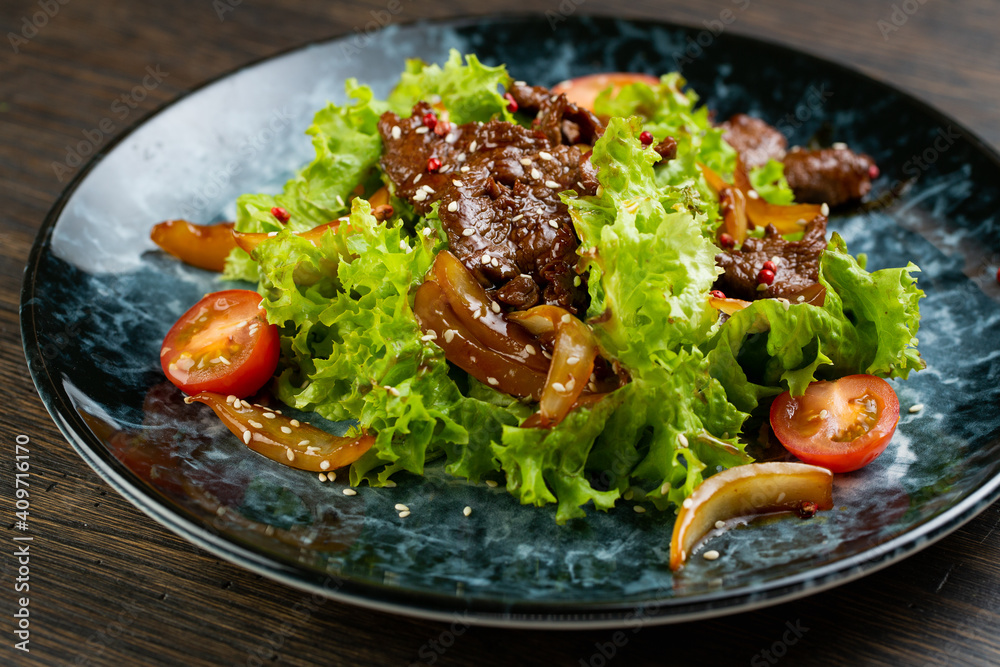 salad of stewed beef, lettuce, pickled peppers and cherry tomatoes. beef salad on a blue marble plate salad of stewed beef, lettuce, pickled peppers and cherry tomatoes. beef salad on a blue marble plate