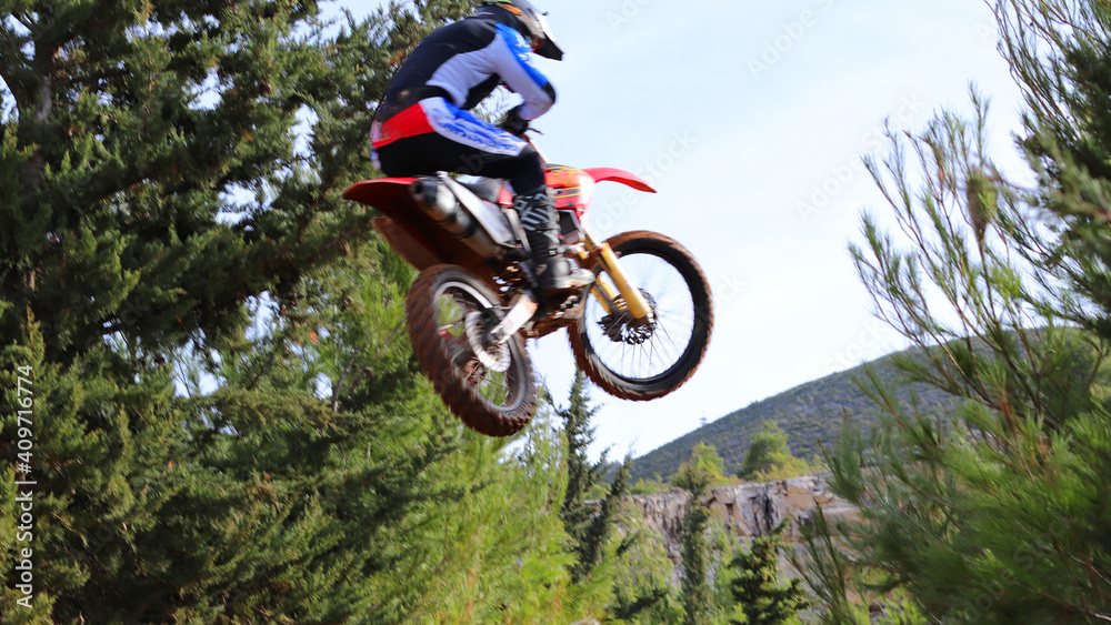 Professional dirt bike motocross rider performing stunts and flying from jump in extreme terrain track Professional dirt bike motocross rider performing stunts and flying from jump in extreme terrain track