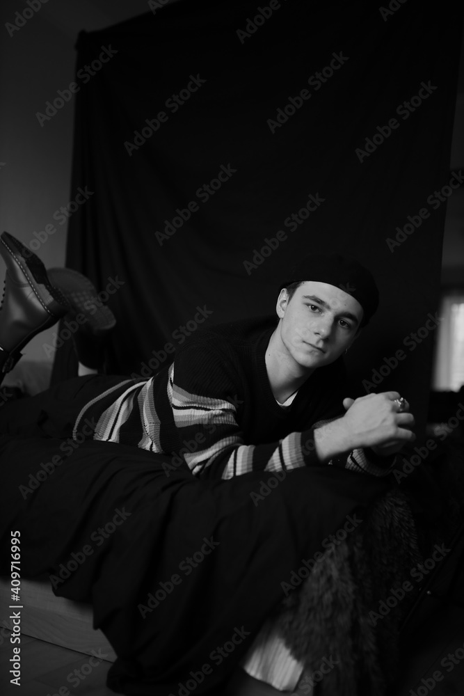 black and white portrait of a young guy. The guy is lying on the bed. a guy of European appearance. Young man. The man is posing.
