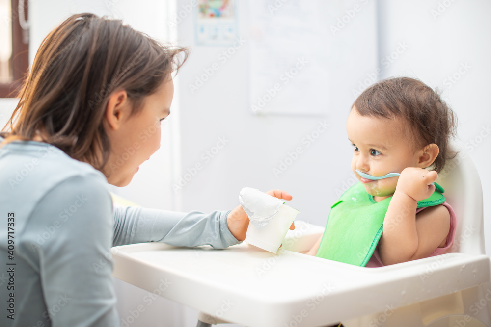 Older sister feeding her younger sister and having fun. Older sister feeding her younger sister and having fun.