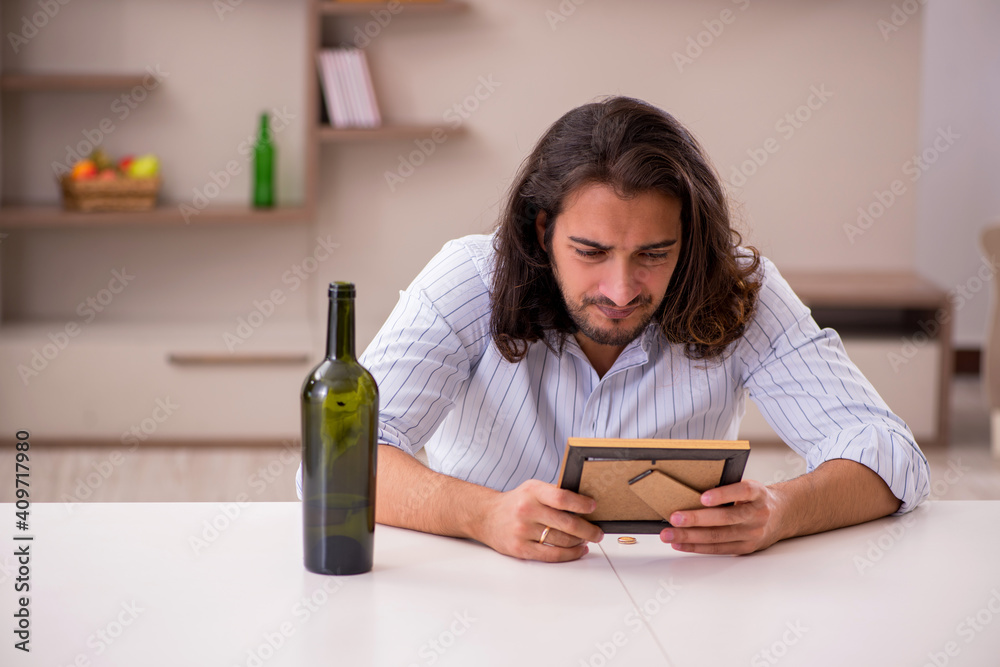 Young man drinking alcohol at home in unhappy love concept Young man drinking alcohol at home in unhappy love concept