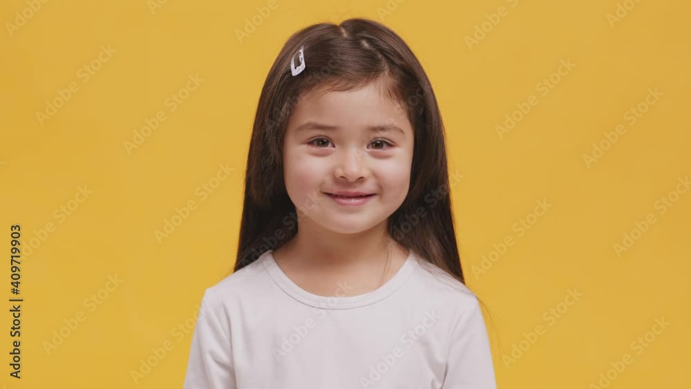 Studio portrait of cute little girl smiling at camera, orange background Studio portrait of cute little girl smiling at camera, orange background