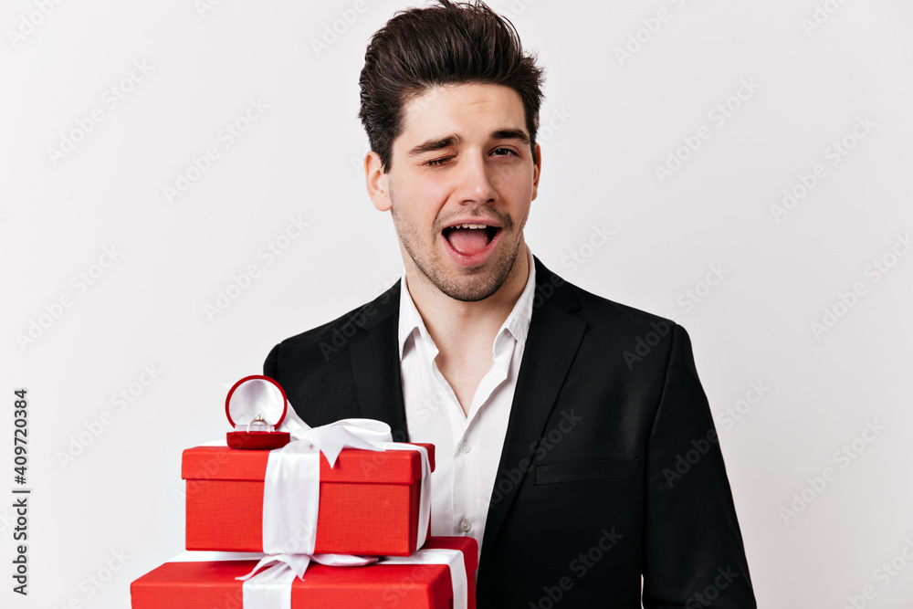 Good-humoured man with cheerful smile posing in valentine's day. Indoor shot of european boy with gift.