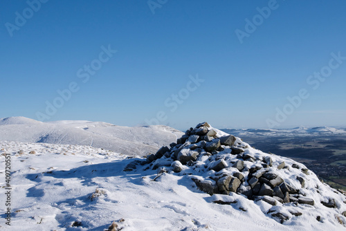 view of snowy mountains with stone mound on a peak in Ochil Hills 