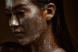 Silver sparkling female make-up, young girl posing with festive glowing glittering body art, close up studio portrait