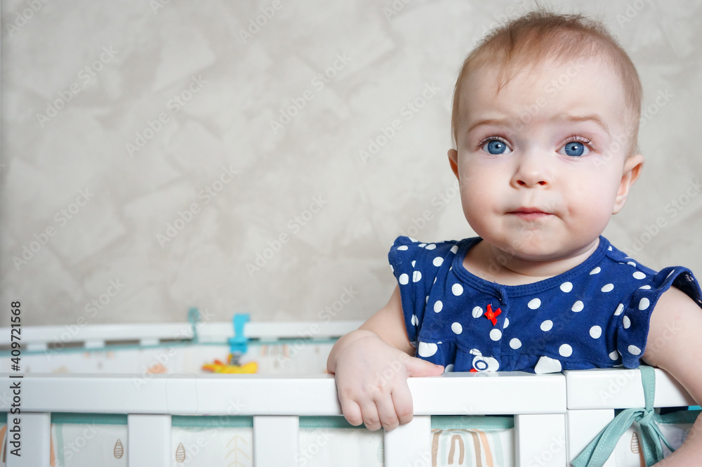 Cute little girl standing in the crib after sleeping. A healthy happy