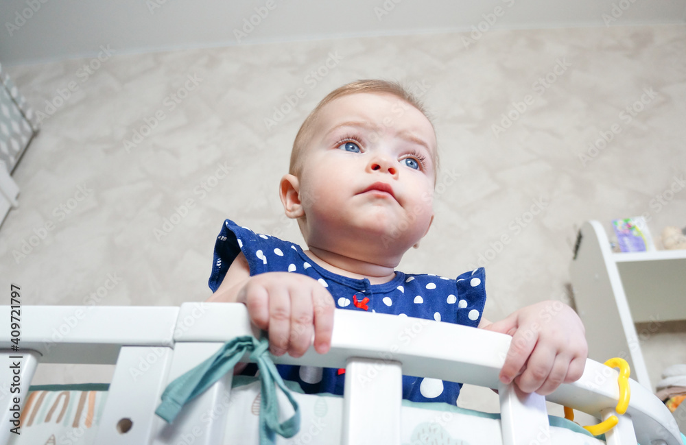 Cute little girl standing in the crib after sleeping. A healthy happy