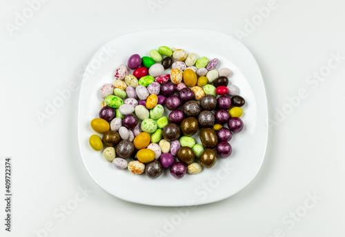 Colorful lollipops on a plate and colorful round candies. Top view white background. Close-up