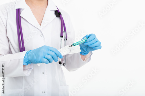 A young nurse in a mask opens a syringe on a white background in a white coat, to make a vaccination, an injection. The concept of vaccination and protection against influenza, from avid, copy space