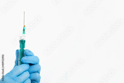 A doctor's hand in a medical glove holds a syringe with a needle to protect against the flu virus. Cvd vaccine. The concept of medicine vaccination treatment with subcutaneous injections, copy space