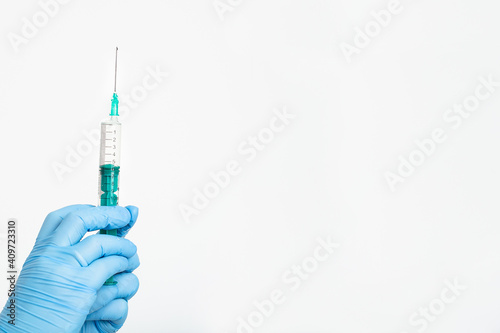A doctor's hand in a medical glove holds a syringe with a needle to protect against the flu virus. Cvd vaccine. The concept of medicine vaccination treatment with subcutaneous injections, copy space