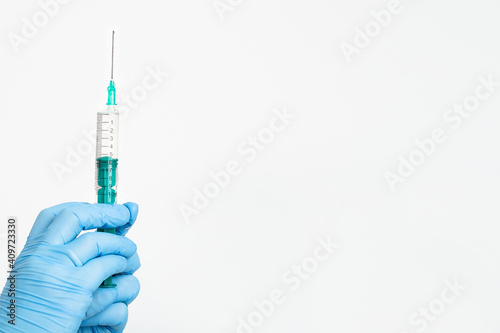 A doctor's hand in a medical glove holds a syringe with a needle to protect against the flu virus. Cvd vaccine. The concept of medicine vaccination treatment with subcutaneous injections, copy space