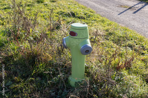 green-yellow neon colored fire hydrant on a meadow, in the daytime without people, hydrants save lives in a fire of buildings