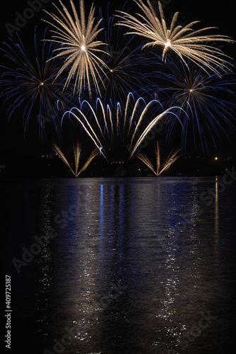 Blue and yellow fireworks reflected in water