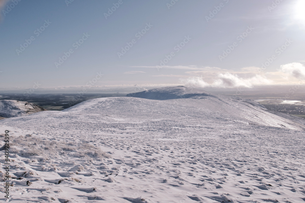 View of a path leading over the top of snow covered hill in Scotland on a bright sunny day