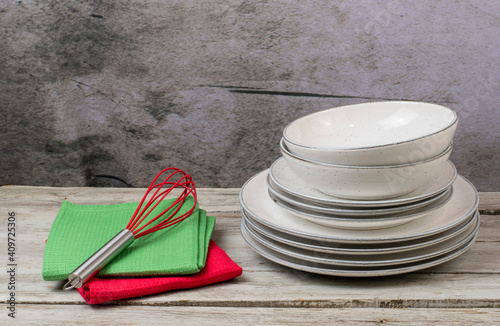 Plates with kitchen towels and cooking utensils on a wooden table with