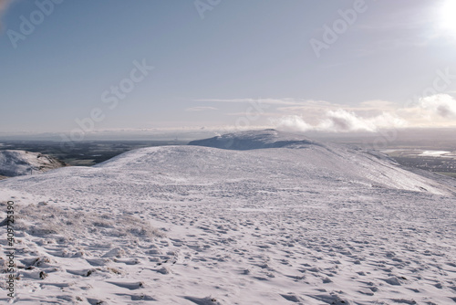 View of a path leading over the top of snow covered hill in Scotland on a bright sunny day