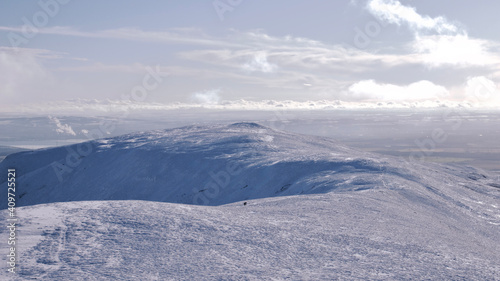 silhouette of an alone walker on top of a snow covered hill in Scotland