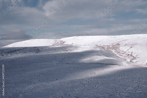 shadow covering half of snow covered meadow in the Ochil Hills © Jitka