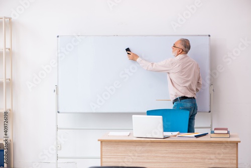 Old male teacher in the classroom in pandemic concept