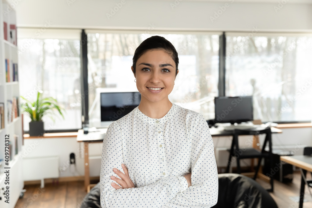 Confident Indian millennial businesswoman posing with hands folded in office. Head shot portrait of happy young female professional, business leader, boss or corporate coach looking at camera. - obrazy, fototapety, plakaty 