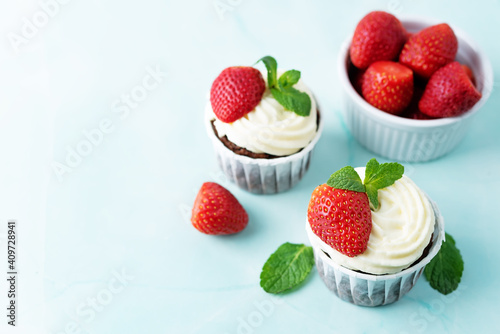 Chocolate cupcakes with cream cheese frosting, mint leaves and strawberries